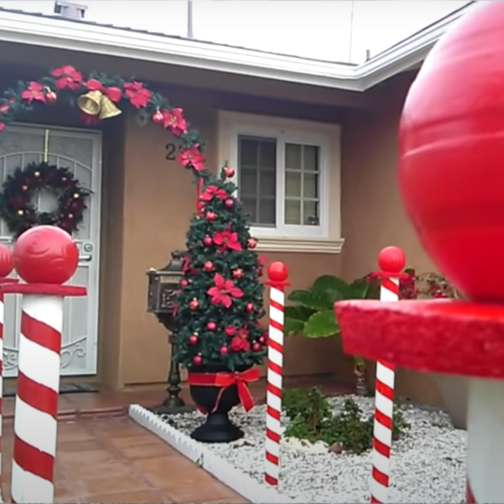 front of a home with a decoration that creates a walkway representing a santa walkway of candy canes