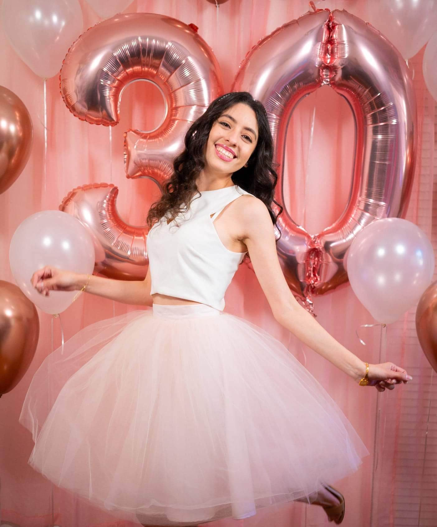 girl infront of a backdrop with pink curtains and balloon numbers